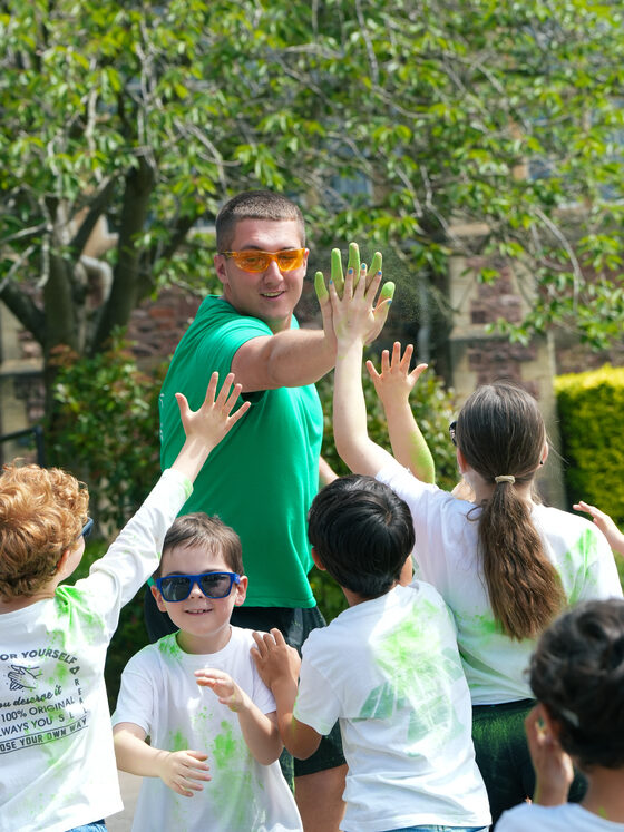 Children high-fiving a uKids coach during a colour run