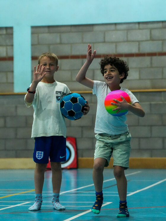 Two children with balls in the sports hall