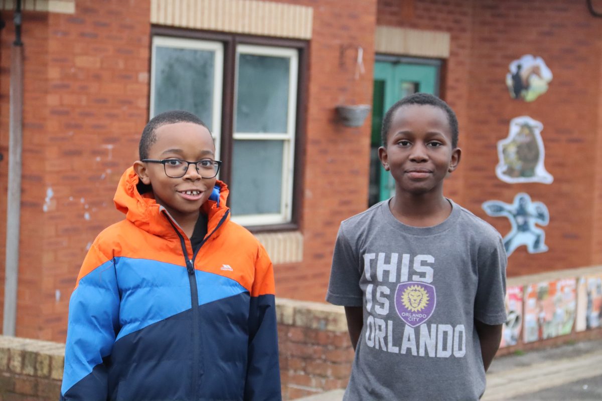 Two smiling boys in the playground outside the school building