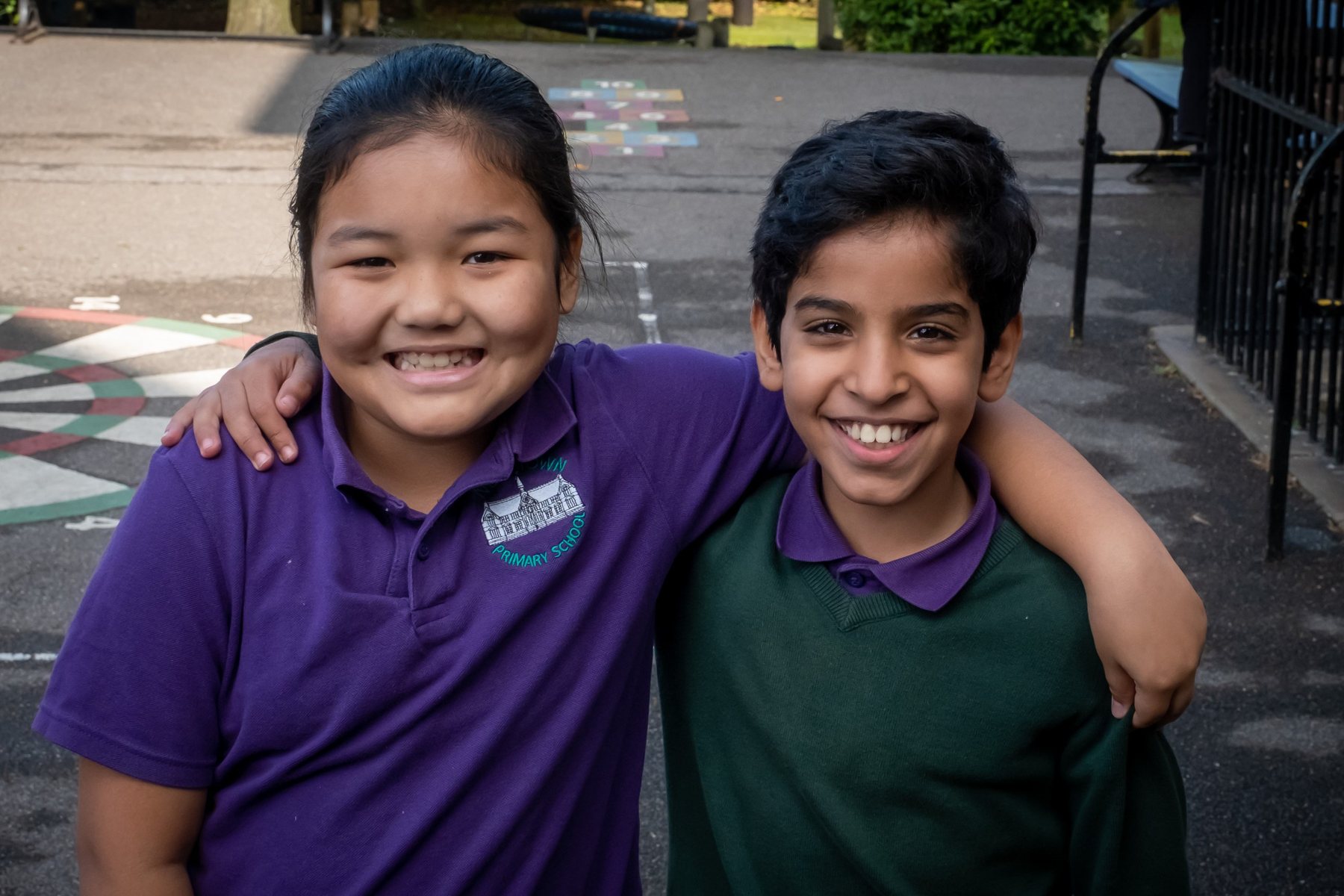 Two smiling children in New Town Primary School uniform in the playground