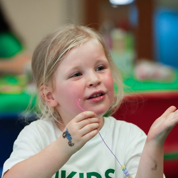A child threading beads onto a string at a uKids craft session
