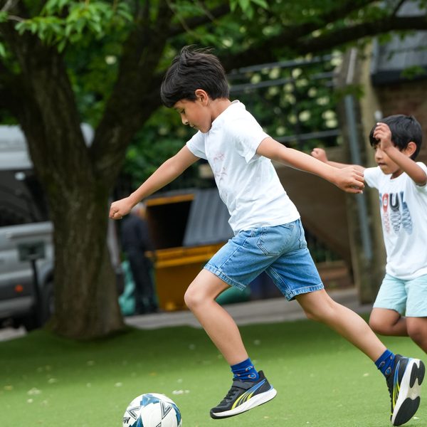 A child dribbling a football on the astro pitch at uKids camp