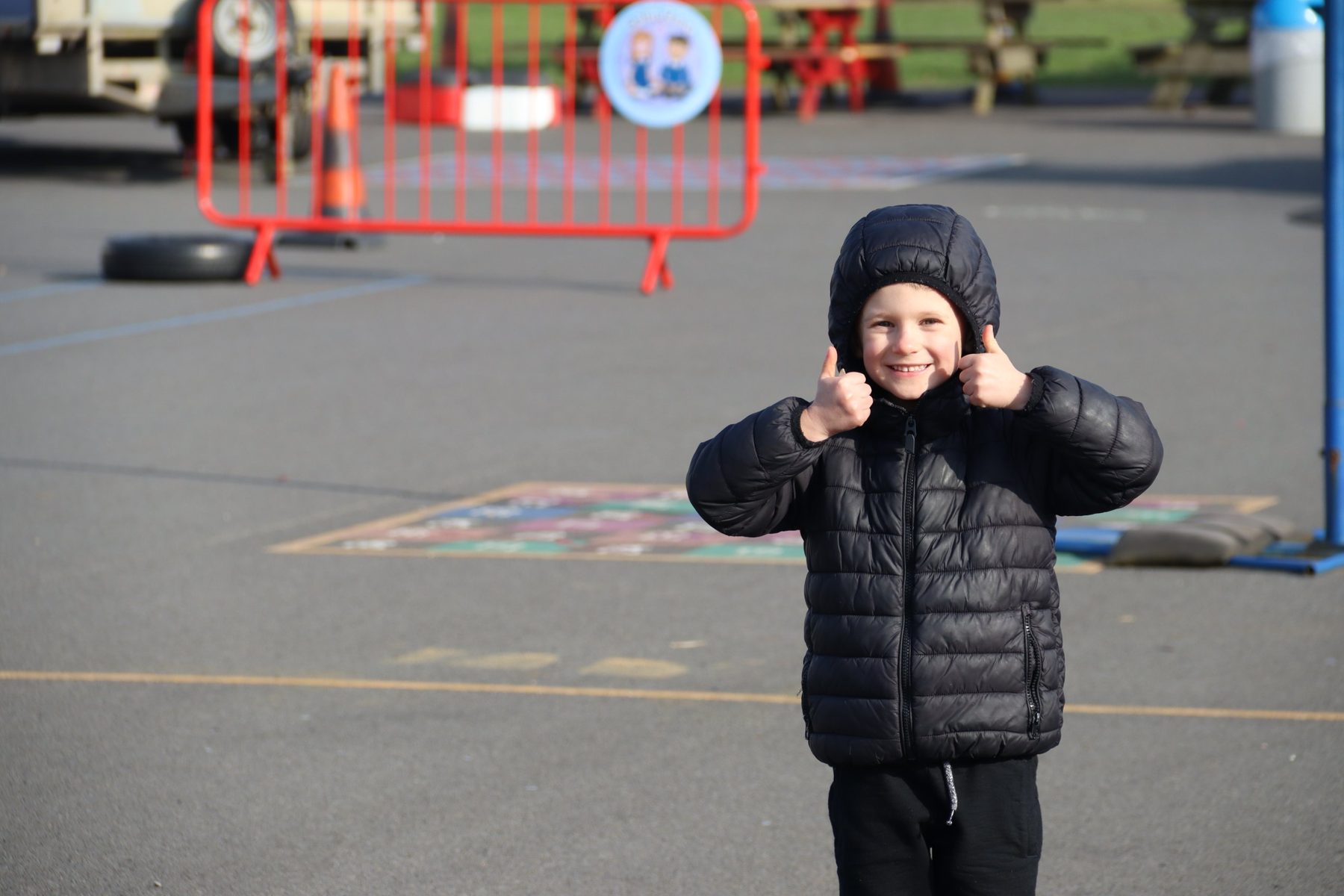 A smiling child giving a thumbs up in the playground at uKids club