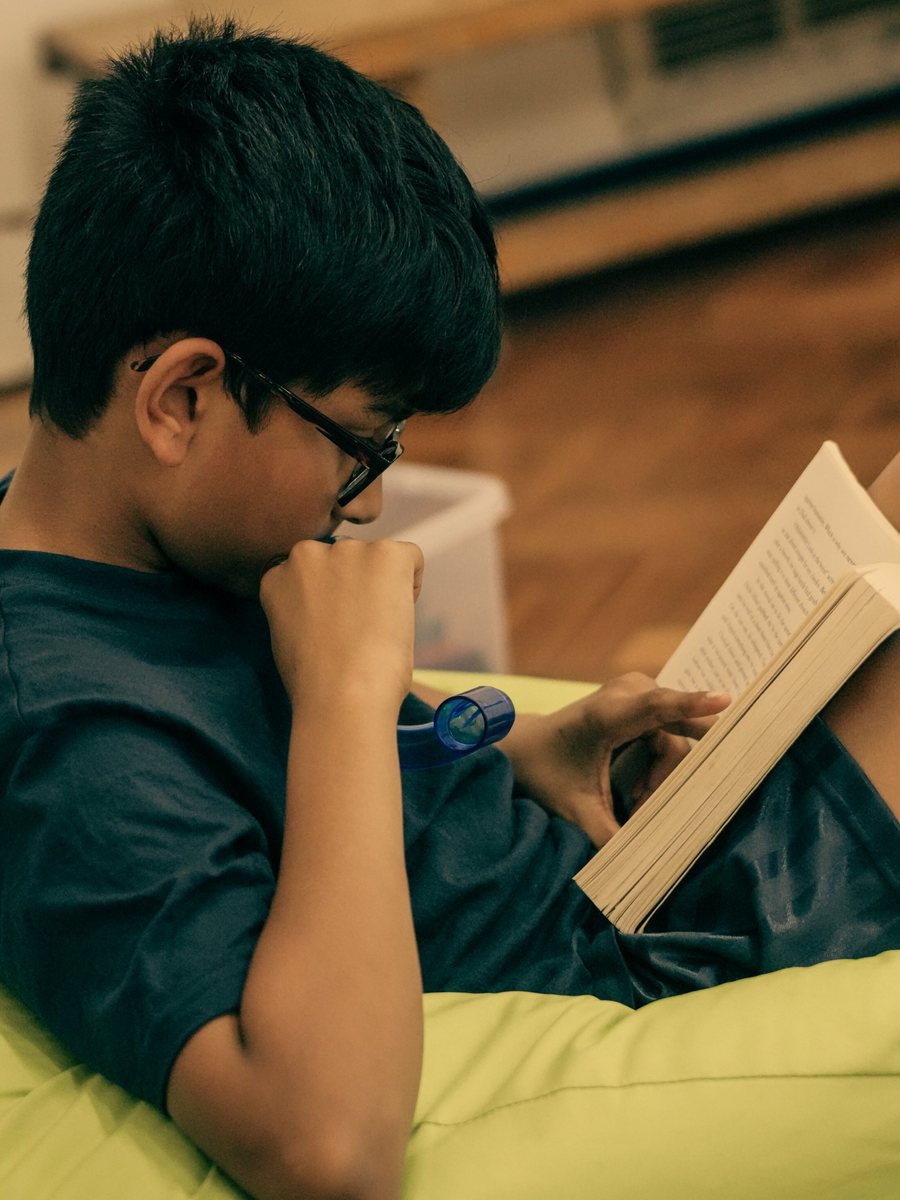 A child reading a book on a beanbag at uKids club at Shinfield St Mary&rsquo;s